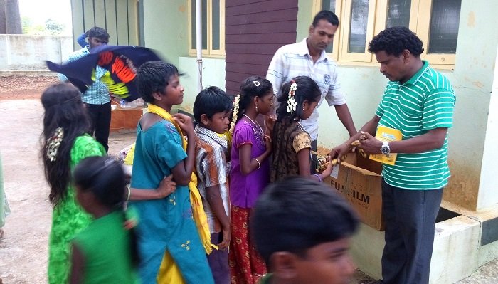 Children receiving items from a VAIGAI facilitator