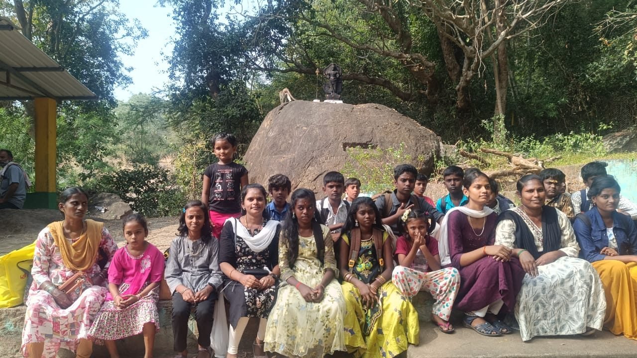 Group photo of women and girls seated in front of a rock