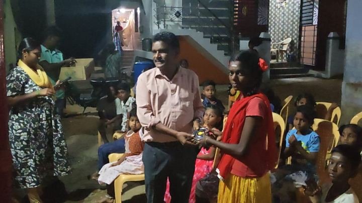 Evening community event with a gift being presented to a girl